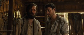 Movie still from “Redeeming Love” (2022), directed by D.J. Caruso – Two men standing next to each other in a room; Medium shot, Low angle