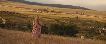 Movie still from “Redeeming Love” (2022), directed by D.J. Caruso – A woman is standing in a field looking out at a valley; Wide shot, Over the shoulder angle