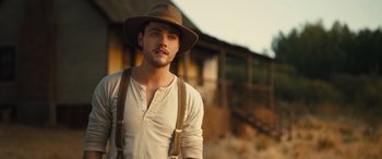 Movie still from “Redeeming Love” (2022), directed by D.J. Caruso – A man wearing a hat and suspenders standing in front of a building; Close Up shot, Low angle