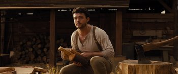 Movie still from “Redeeming Love” (2022), directed by D.J. Caruso – A man kneeling down holding a wooden log; Medium shot, Low angle