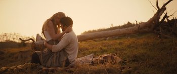Movie still from “Redeeming Love” (2022), directed by D.J. Caruso – A man and a woman sitting on the ground in a field; Medium shot, High angle