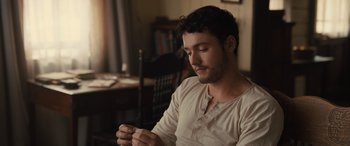 Movie still from “Redeeming Love” (2022), directed by D.J. Caruso – A man sitting at a table holding a piece of paper; Close Up shot, High angle