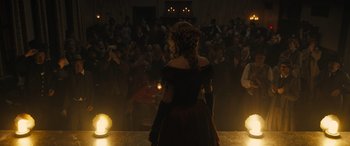 Movie still from “Redeeming Love” (2022), directed by D.J. Caruso – A woman in a black dress standing in front of an audience; Wide shot, Over the shoulder angle