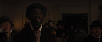 Movie still from “Redeeming Love” (2022), directed by D.J. Caruso – A man with a beard and a hat in front of a group of people; Close Up shot, Low angle