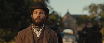 Movie still from “Redeeming Love” (2022), directed by D.J. Caruso – A man with a beard wearing a suit and a hat; Close Up shot, Low angle