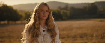 Movie still from “Redeeming Love” (2022), directed by D.J. Caruso – A beautiful young woman with long blonde hair standing on top of a field; Close Up shot, Low angle