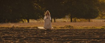 Movie still from “Redeeming Love” (2022), directed by D.J. Caruso – A woman kneeling down in the dirt near a tree; Wide shot, Low angle