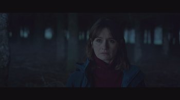 A woman is standing in the dark looking at the camera