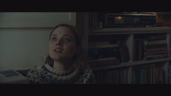 A girl is sitting in front of a book shelf