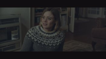 A woman in a sweater is standing in a living room