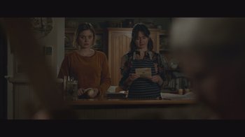 Two women standing in a kitchen looking at an ipad