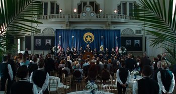 Movie still from “Bad Lieutenant: Port of Call New Orleans” (2009), directed by Werner Herzog – A group of people sitting in front of an audience; Extreme Wide shot, High angle