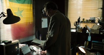 Movie still from “Bad Lieutenant: Port of Call New Orleans” (2009), directed by Werner Herzog – A man standing in front of a laptop computer in an office setting; Medium shot, Over the shoulder angle