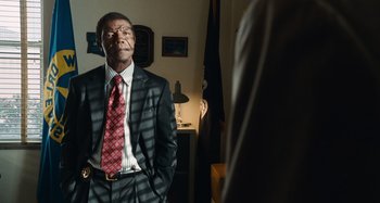 Movie still from “Bad Lieutenant: Port of Call New Orleans” (2009), directed by Werner Herzog – A man in a suit and tie standing in a room; Medium shot, Over the shoulder angle