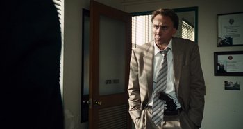 Movie still from “Bad Lieutenant: Port of Call New Orleans” (2009), directed by Werner Herzog – A man in a suit and tie standing in front of a door; Medium shot, Over the shoulder angle