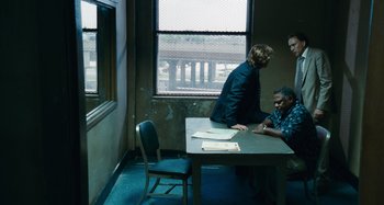 Movie still from “Bad Lieutenant: Port of Call New Orleans” (2009), directed by Werner Herzog – Three people sitting at a table with papers on it; Wide shot, Over the shoulder angle