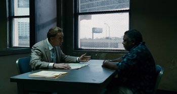 Movie still from “Bad Lieutenant: Port of Call New Orleans” (2009), directed by Werner Herzog – Two men sitting at a table talking to each other; Medium shot, Over the shoulder angle