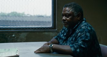 Movie still from “Bad Lieutenant: Port of Call New Orleans” (2009), directed by Werner Herzog – A man sitting at a table in front of a window; Medium shot, Over the shoulder angle