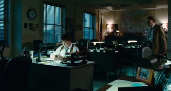 Movie still from “Bad Lieutenant: Port of Call New Orleans” (2009), directed by Werner Herzog – A man sitting at a desk in an office setting; Wide shot, High angle