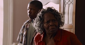 Movie still from “Bad Lieutenant: Port of Call New Orleans” (2009), directed by Werner Herzog – An older woman and a young man standing next to each other; Close Up shot, Over the shoulder angle