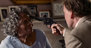 Movie still from “Bad Lieutenant: Port of Call New Orleans” (2009), directed by Werner Herzog – An older woman and a man holding a gun up to their eyes; Close Up shot, High angle