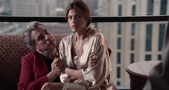 Movie still from “Bad Lieutenant: Port of Call New Orleans” (2009), directed by Werner Herzog – An older man and a younger woman sitting on a couch in front of a window; Medium shot, Over the shoulder angle