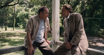 Movie still from “Bad Lieutenant: Port of Call New Orleans” (2009), directed by Werner Herzog – Two men are talking to each other in a park; Medium shot, Low angle