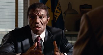 Movie still from “Bad Lieutenant: Port of Call New Orleans” (2009), directed by Werner Herzog – A man in a suit and tie talking to someone; Close Up shot, Over the shoulder angle