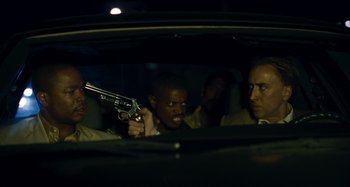 Movie still from “Bad Lieutenant: Port of Call New Orleans” (2009), directed by Werner Herzog – A group of men standing in a car holding guns; Close Up shot, Over the shoulder angle