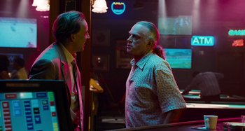 Movie still from “Bad Lieutenant: Port of Call New Orleans” (2009), directed by Werner Herzog – Two men are talking in a bar with neon lights in the background; Medium shot, Over the shoulder angle