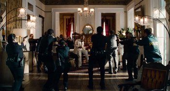 Movie still from “Bad Lieutenant: Port of Call New Orleans” (2009), directed by Werner Herzog – A group of people standing in a living room; Wide shot, Over the shoulder angle