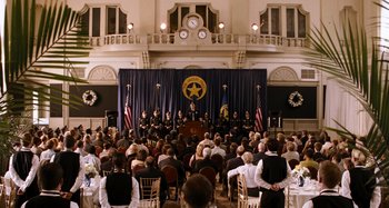 Movie still from “Bad Lieutenant: Port of Call New Orleans” (2009), directed by Werner Herzog – A crowd of people sitting and standing in front of a stage; Extreme Wide shot, High angle
