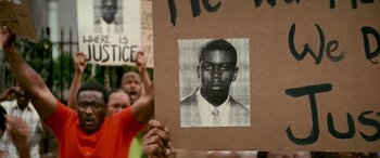 Movie still from “Remember the Titans” (2000), directed by Boaz Yakin – A person holds up a sign with an image of a man; Close Up shot, High angle