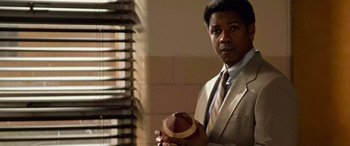 Movie still from “Remember the Titans” (2000), directed by Boaz Yakin – A man in a suit and tie holding a football; Close Up shot, Low angle