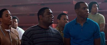Movie still from “Remember the Titans” (2000), directed by Boaz Yakin – A group of men standing next to each other in a room; Medium shot, Low angle