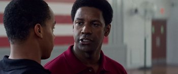 Movie still from “Remember the Titans” (2000), directed by Boaz Yakin – A man in a red shirt is standing next to another man in a red shirt; Close Up shot, Over the shoulder angle