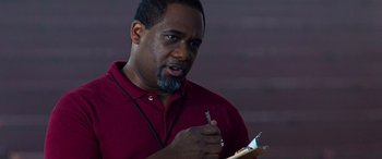 Movie still from “Remember the Titans” (2000), directed by Boaz Yakin – A man in a red shirt is holding a pen; Close Up shot, Low angle