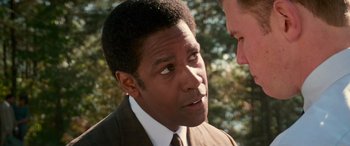 Movie still from “Remember the Titans” (2000), directed by Boaz Yakin – A man wearing a suit and tie talking to another man wearing a suit and tie; Close Up shot, Over the shoulder angle