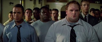 Movie still from “Remember the Titans” (2000), directed by Boaz Yakin – A group of men standing next to each other in a room; Medium shot, Low angle
