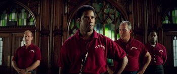 Movie still from “Remember the Titans” (2000), directed by Boaz Yakin – A man in a red shirt is standing next to another man in a red shirt; Close Up shot, Low angle