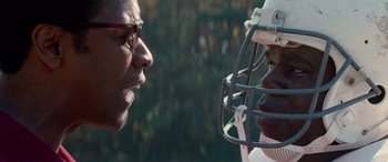 Movie still from “Remember the Titans” (2000), directed by Boaz Yakin – A man and a woman face each other with a football helmet on; Close Up shot, Over the shoulder angle