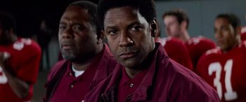Movie still from “Remember the Titans” (2000), directed by Boaz Yakin – A man in a red shirt is looking into the camera; Close Up shot, Low angle