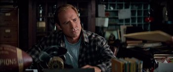 Movie still from “Remember the Titans” (2000), directed by Boaz Yakin – A man sitting at a table looking at a phone; Close Up shot, Over the shoulder angle