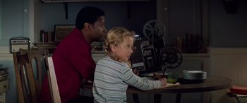 Movie still from “Remember the Titans” (2000), directed by Boaz Yakin – A man and a little girl sitting in front of a projector; Medium shot, Over the shoulder angle