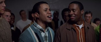 Movie still from “Remember the Titans” (2000), directed by Boaz Yakin – A group of men standing next to each other in a room; Medium shot, High angle