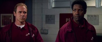 Two men in red jackets standing next to each other in a room