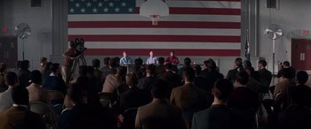 Movie still from “Remember the Titans” (2000), directed by Boaz Yakin – A group of people sitting in front of an american flag; Wide shot, High angle