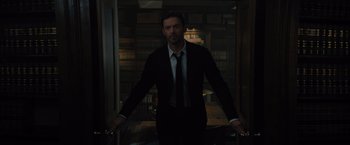 Movie still from “Reminiscence” (2021), directed by Lisa Joy – A man in a suit and tie holding a pair of handles; Medium shot, Low angle