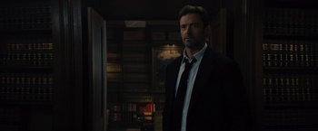 Movie still from “Reminiscence” (2021), directed by Lisa Joy – A man in a suit and tie standing in a room; Medium shot, Low angle