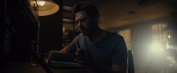 Movie still from “Reminiscence” (2021), directed by Lisa Joy – A man sitting at a table writing on a book; Close Up shot, Low angle